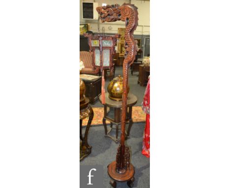 A contemporary Chinese hardwood standard lamp, carved in the form of a dragon on a circular base, holding a hexagonal lantern