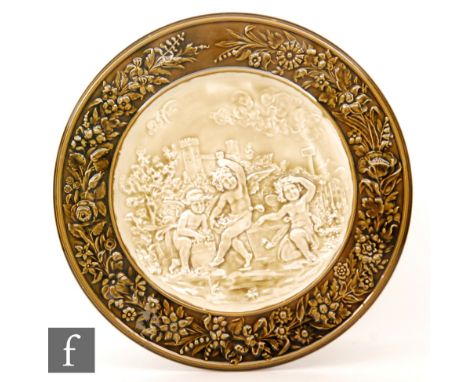 An early 20th Century Arnold and Ludwig Richard Schutz majolica charger decorated in relief with a scene of three winged cher