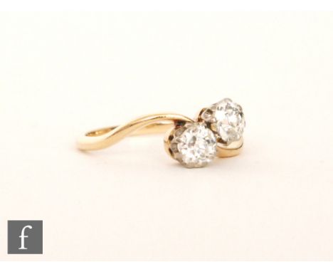A mid 20th Century 18ct diamond two stone ring, claw set old cut stones to a slight twist, ring size J. S/D. 