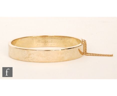 A continental 14ct hinged bangle of plain form, with engraved inscription to one side, weight 28g.