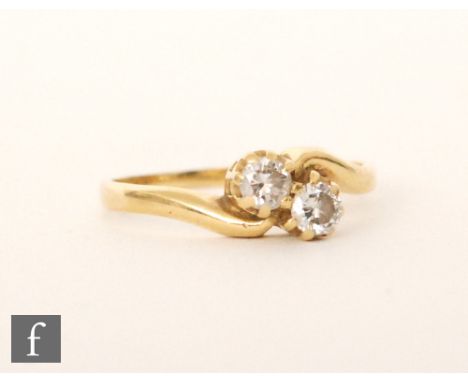 An 18ct hallmarked diamond two stone cross over ring, brilliant cut claw set stones to plain shoulders, ring size M. 