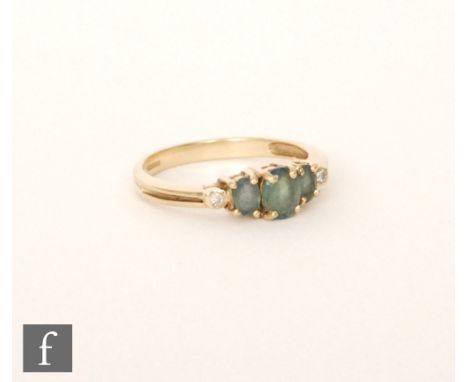 A 9ct hallmarked green alexandirite and diamond five stone ring, three central graduating alexandrite with a single diamond t