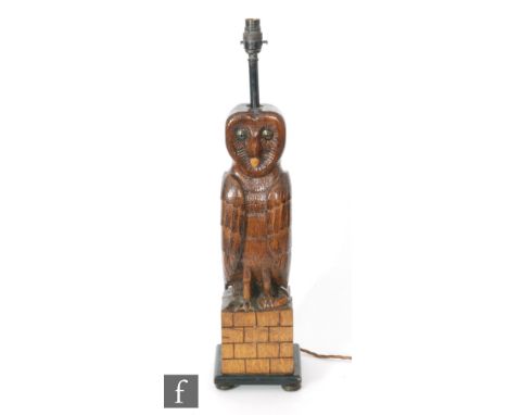 An early 20th Century carved oak table lamp in the form of an owl perched upon a plinth and holding a mouse, overall height i