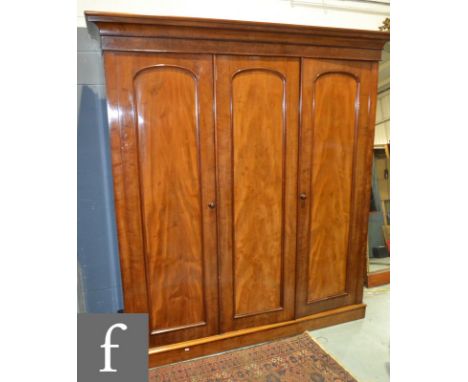 A late 19th Century mahogany triple door compactum, the three arch panelled doors enclosing three pull-out slide trays, two s