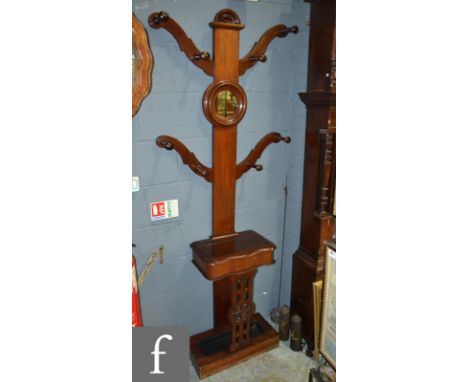 A Victorian totem style hall stand, with central circular mirror flaked by hat and coat hooks above a glove box and stick sta
