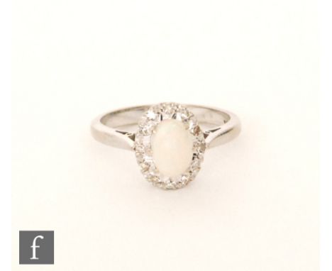 An 18ct opal and diamond cluster ring, central oval cabochon opal claw set within a twelve stone diamond surround, ring size 