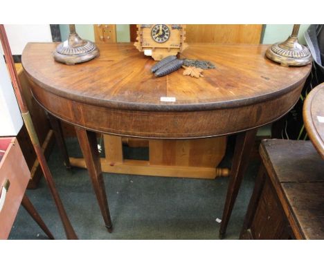 A 19th century demi-lune card table with decorative inlaid top and apron on plain tapering legs with spade feet.