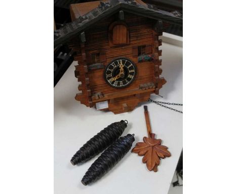 A traditional wooden Cuckoo clock, with pendulum and pine cone weights