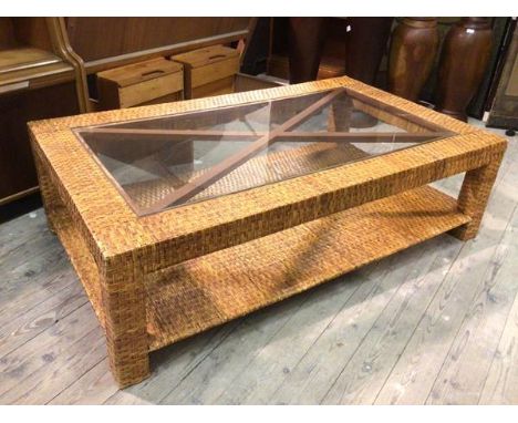 A modern coffee table with woven cane frame and glass panel top above a lower tier, on block feet (44cm x 150cm x 90cm)