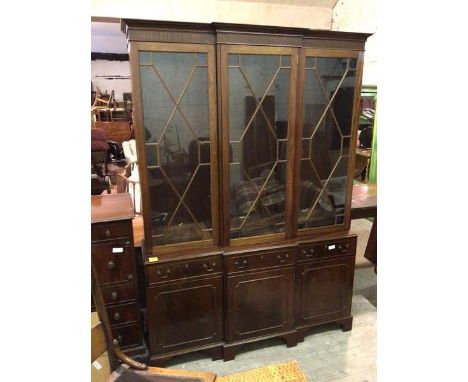 A Georgian inspired breakfront bookcase, the moulded cornice above three glazed doors with adjustable shelved interior, the b