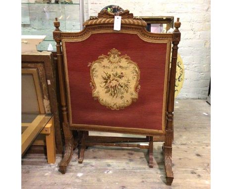 An Edwardian firescreen, the shaped top with carved surmount, knob finials above reeded fluted tapering columns flanking an e