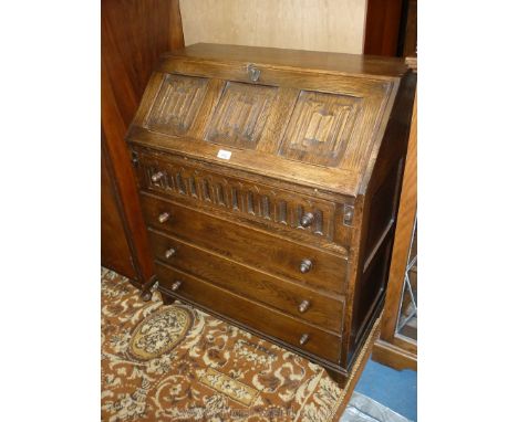 A Priory Oak style Bureau, the three panelled slope with linen fold design revealing an interior with pigeon-holes and one sm
