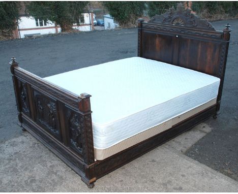 A 19th Century Dutch Oak double bedstead, the headboard with two raised and fielded panels and a carved pediment depicting a 