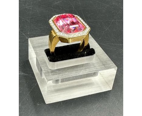 A Fashion ring in gold marked 18 with central pink stone and white stone surround. Approximate Total weight 17g Size P