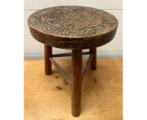 An Arts and Crafts style stool with carved circular top on tripod legs (H28cm Dia24cm)