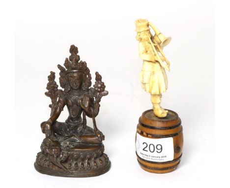 A bronze Tibetan Buddha figure and a late 19th century ivory trumpeter figure, standing on a barrel 