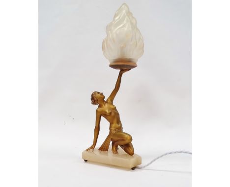 Art Deco table lamp - A gilt spelter table lamp modelled as a scantily clad lady holding aloft a flame moulded clear glass sh