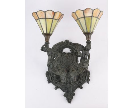 Bronze wall sconce in the form of two winged women emerging from a lattice surrounded by flowering scrollwork. The women hold