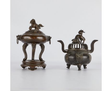 Group of two Chinese bronze tripod censers, one with a wooden stand. Each topped by foo dog finials.Provenance: From the Esta