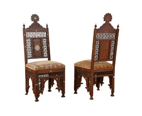 Pair of Syrian mother of pearl inlaid wooden side chairs. The intricately carved wood is inlaid with geometric designs in mot