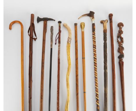 Group of twelve carved wooden canes and walking sticks including one with a hatchet grip and one with a hidden compartment th