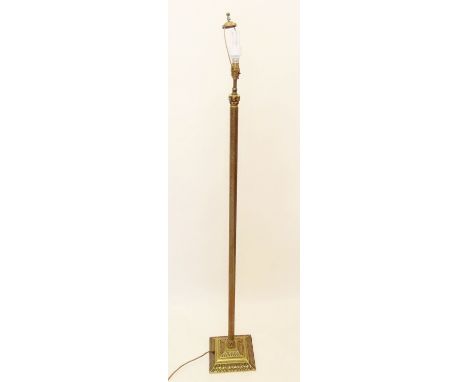 A brass standard lamp with decorative embossed design