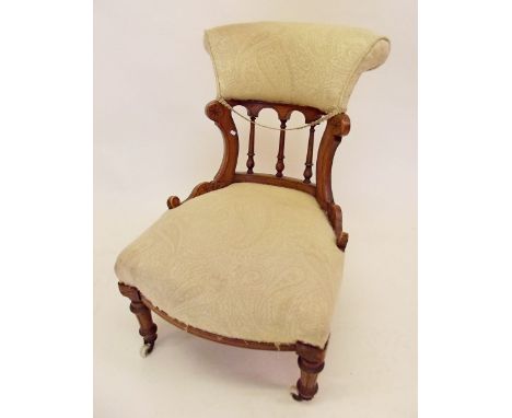 A Victorian cream upholstered spindle and arch back nursing chair on turned supports