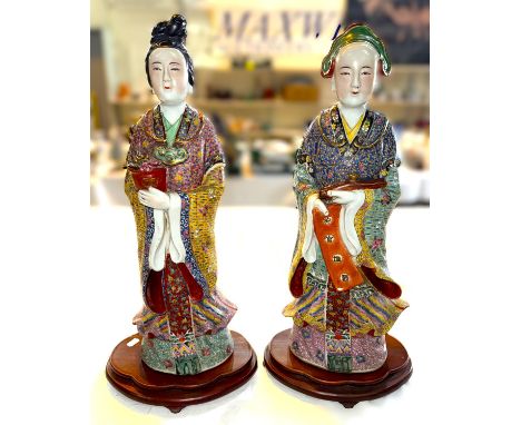A large pair of Chinese ceramic figures on stands, polychrome decoration to their traditional robes, height 58cm and 57cm.
