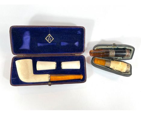 A cased Vienna made amber and clay pipe with to extra fittings, a cased amber and Meerschaum cigarette holder and another
