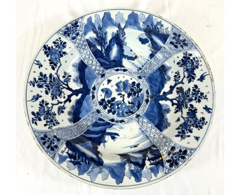A Chinese Kangxi period blue charger with blue and white decoration of trees and flowers, flower mark to base 38cm (chipping 