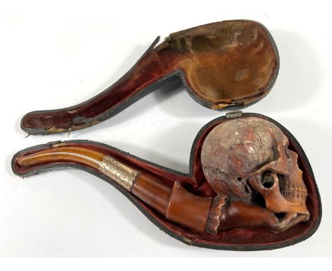 A cased&nbsp;amber and Meerschaum pipe in the form of a skull with chased silver mounts, length 20cm.