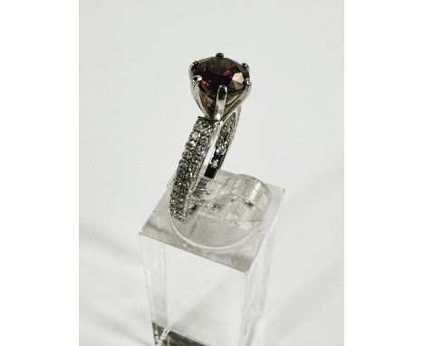 A white metal dress ring with amethyst in raised claw setting, 2 rows of small diamonds to each shoulder, stamped '14K', 3,29