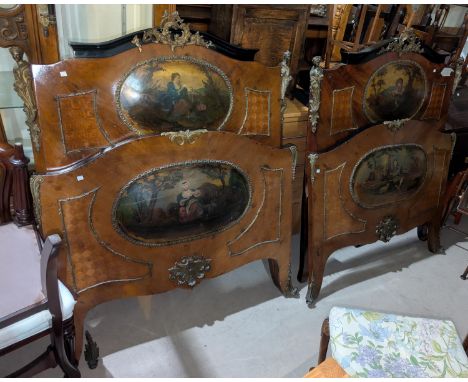 A pair of late 19th/early 20th century Louise XV 1/4 veneered single beds with extensive ormolu panels painted with 18th cent