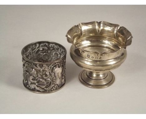 NAPKIN RING ETC.
A late Victorian silver napkin ring, embossed with playing cherubs, London 1891 & an Edwardian silver pedest