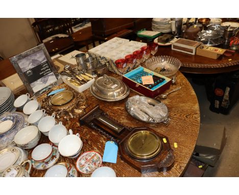 A collection of metal ware to include cutlery, entreé dishes, a photo frame, an ornate wall clock, an oak cased barometer etc