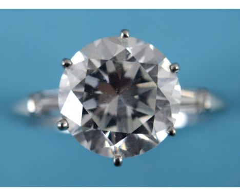 A diamond ring, the large brilliant cut centre stone set in a white coloured metal mount, the shoulders set with baguette cut