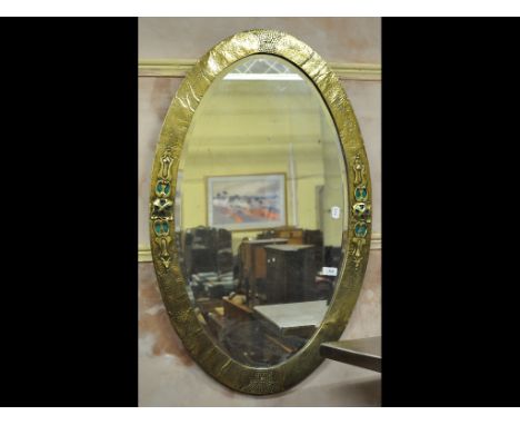An Arts and Crafts brass and enamel oval wall mirror, 97 cm wide
