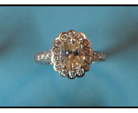 An 18ct white gold and diamond cluster ring, the large oval diamond within a brilliant cut flowerhead, approx. ring size M½  