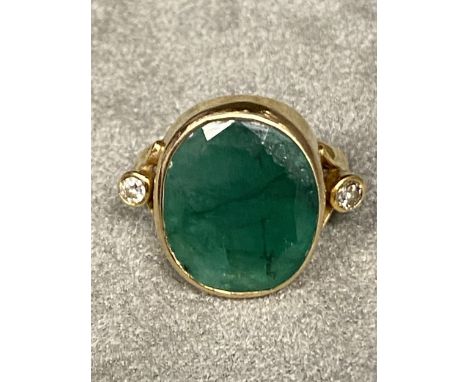 Unmarked yellow metal emerald and diamond ladies dress ring, central oval free cut emerald , 14 mm  by 18mm in collar setting