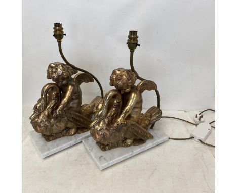 An ornate pair of table lamps styled as winged cherubs on a swan, with cream lamp shades15cm x 30.5 cm at the base32cm high t