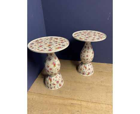 A pair of floral decorated pedestal and circular top ceramic side tables. one has a chip. general wear.