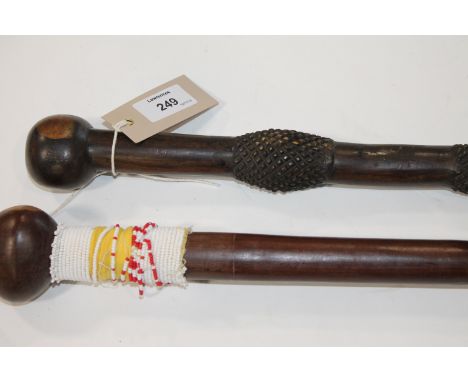 TWO AFRICAN HARDWOOD CLUBS. Two hardwood African stick-clubs with bulbous tops. The first 35.1/4" long with bead decoration b