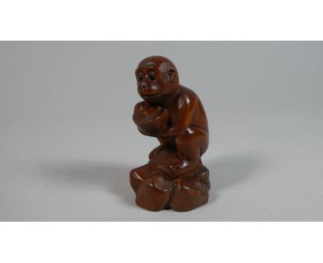 A Carved Wooden Netsuke in the form of a Monkey Set on Naturalistic Base Clutching Coconut, 6cm High 