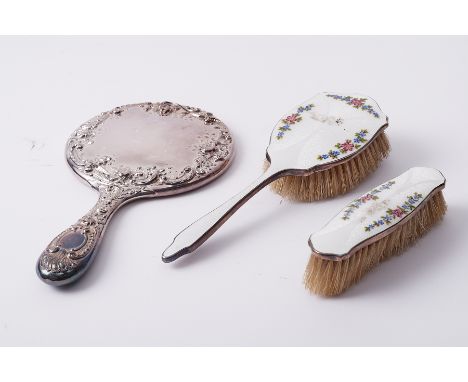 A silver hand mirror together with two silver and enamel brushes (3).