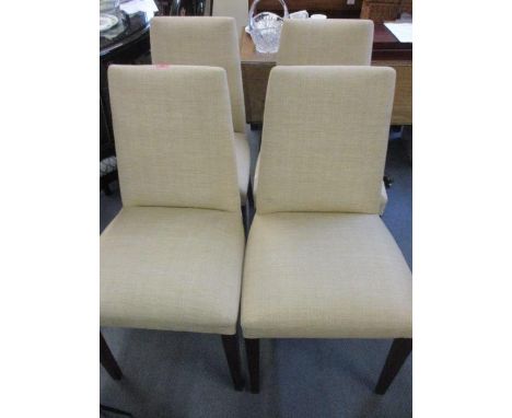 A set of four modern dining chairs with a gold coloured fabric and stained mahogany legs 