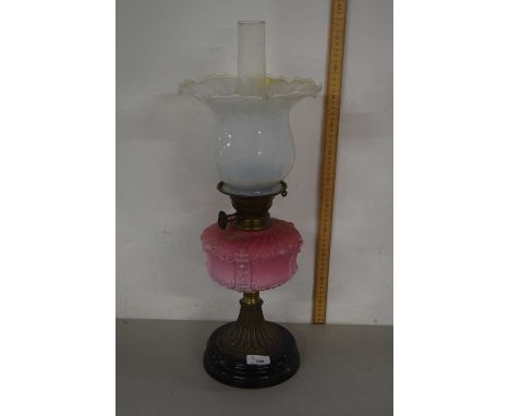 An oil lamp with vaseline tinted glass shade, opaque glass font and brass base