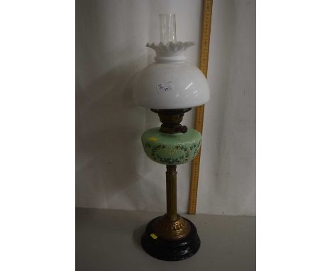 An oil lamp with green glass font and frilled glass shade