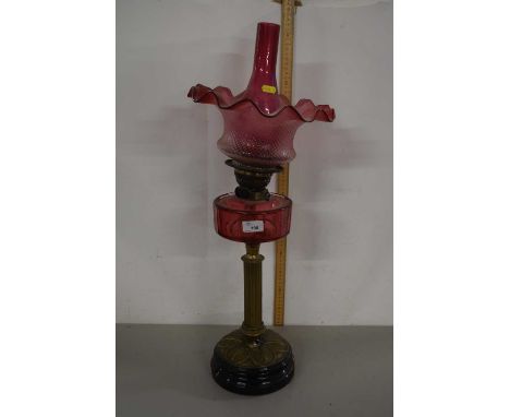 A cranberry glass oil lamp with brass base