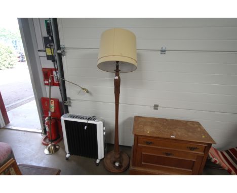 A carved wooden standing lamp and shade