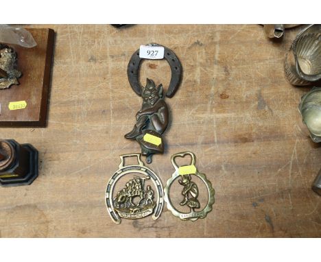 A pixie door knocker, two horse brasses and a small horse shoe